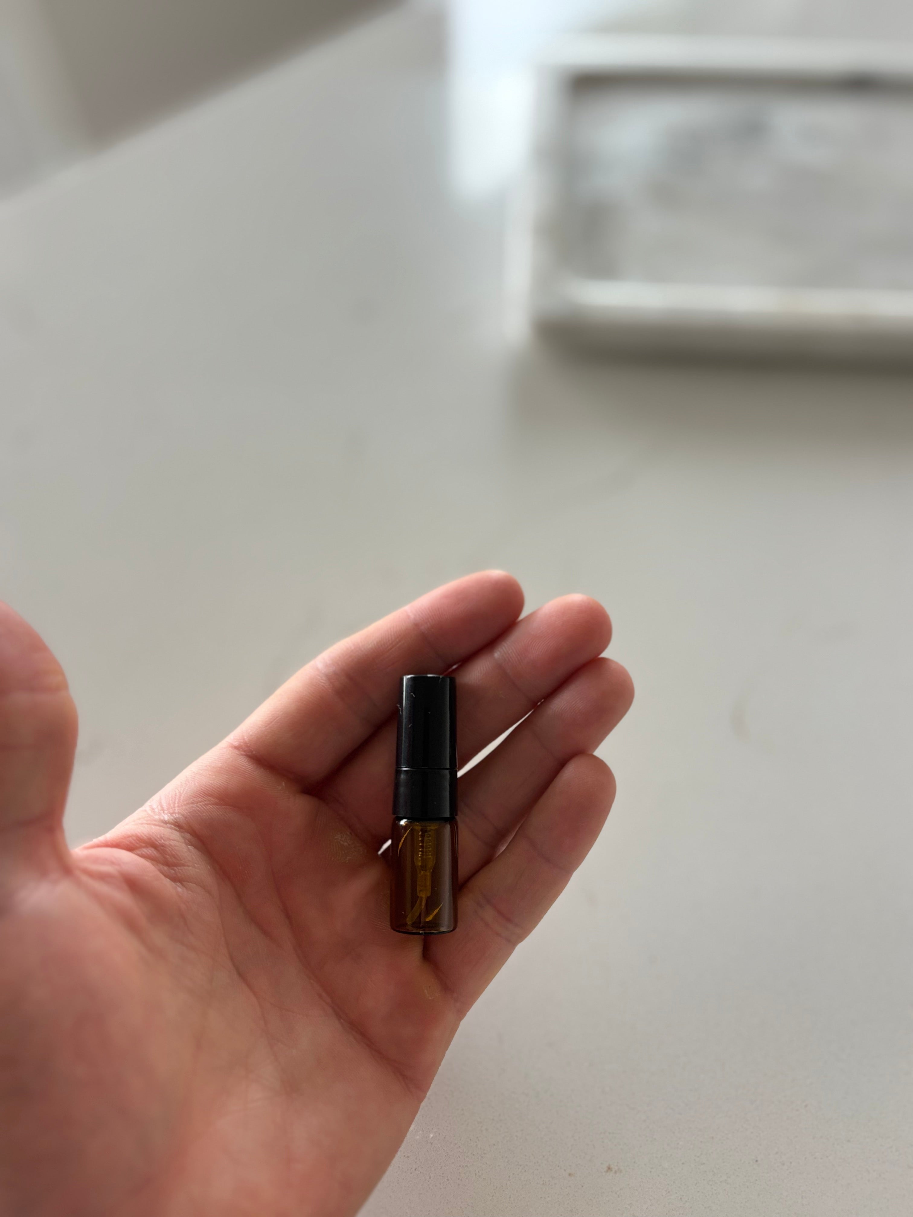 Hand holding a small brown bottle against a white background