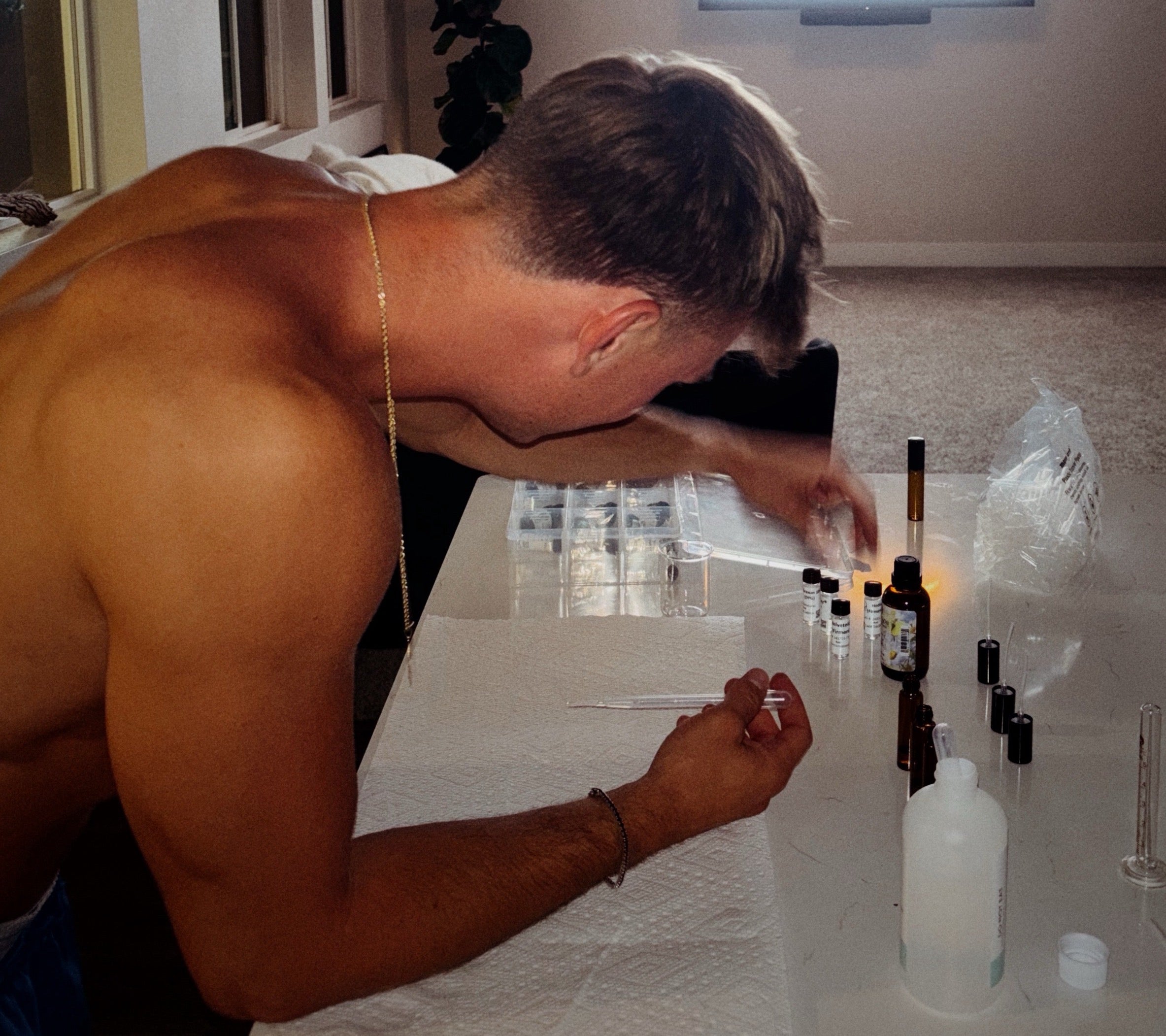 Man working with small bottles on a table in a room.