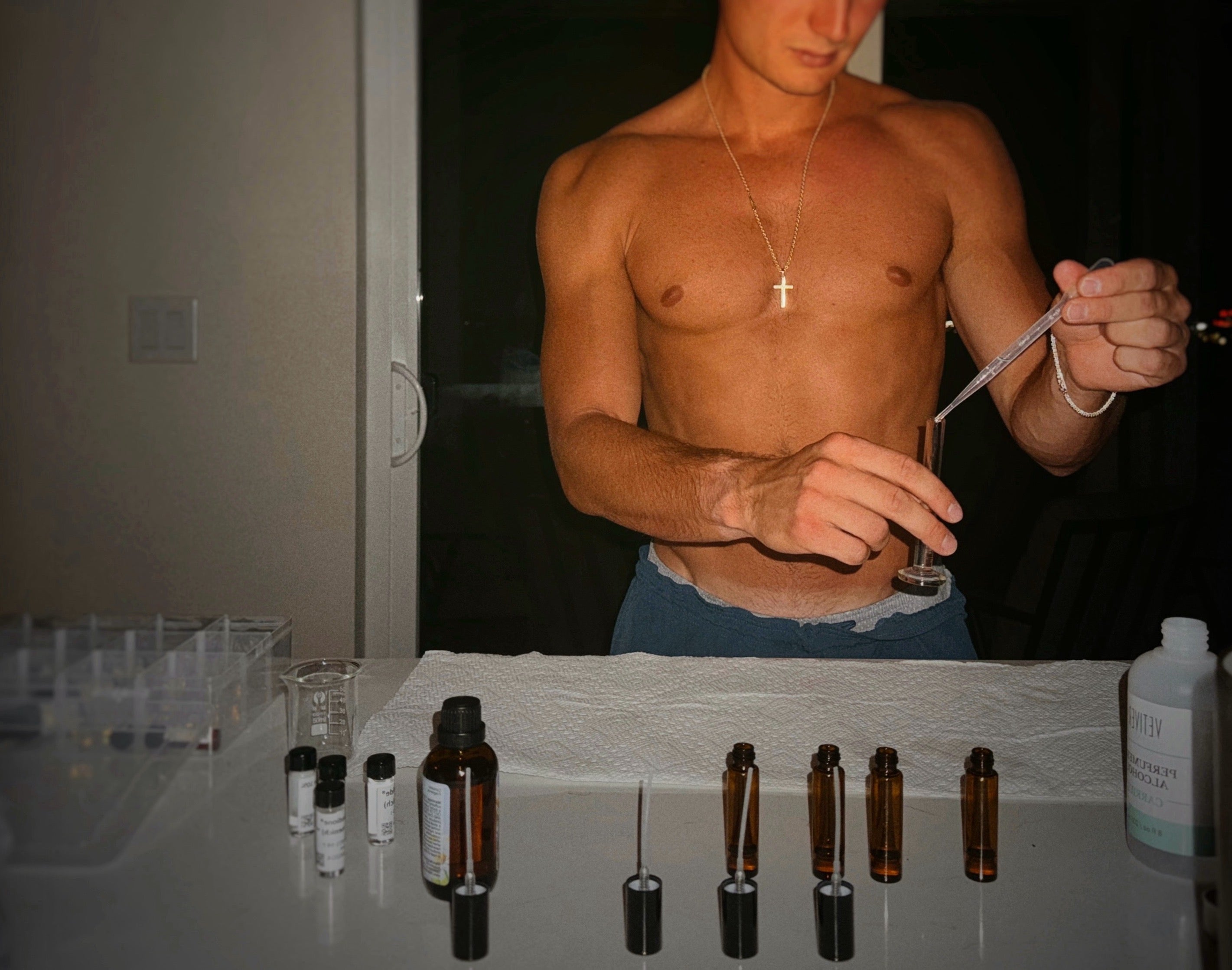 Man holding a dropper with small bottles on a table