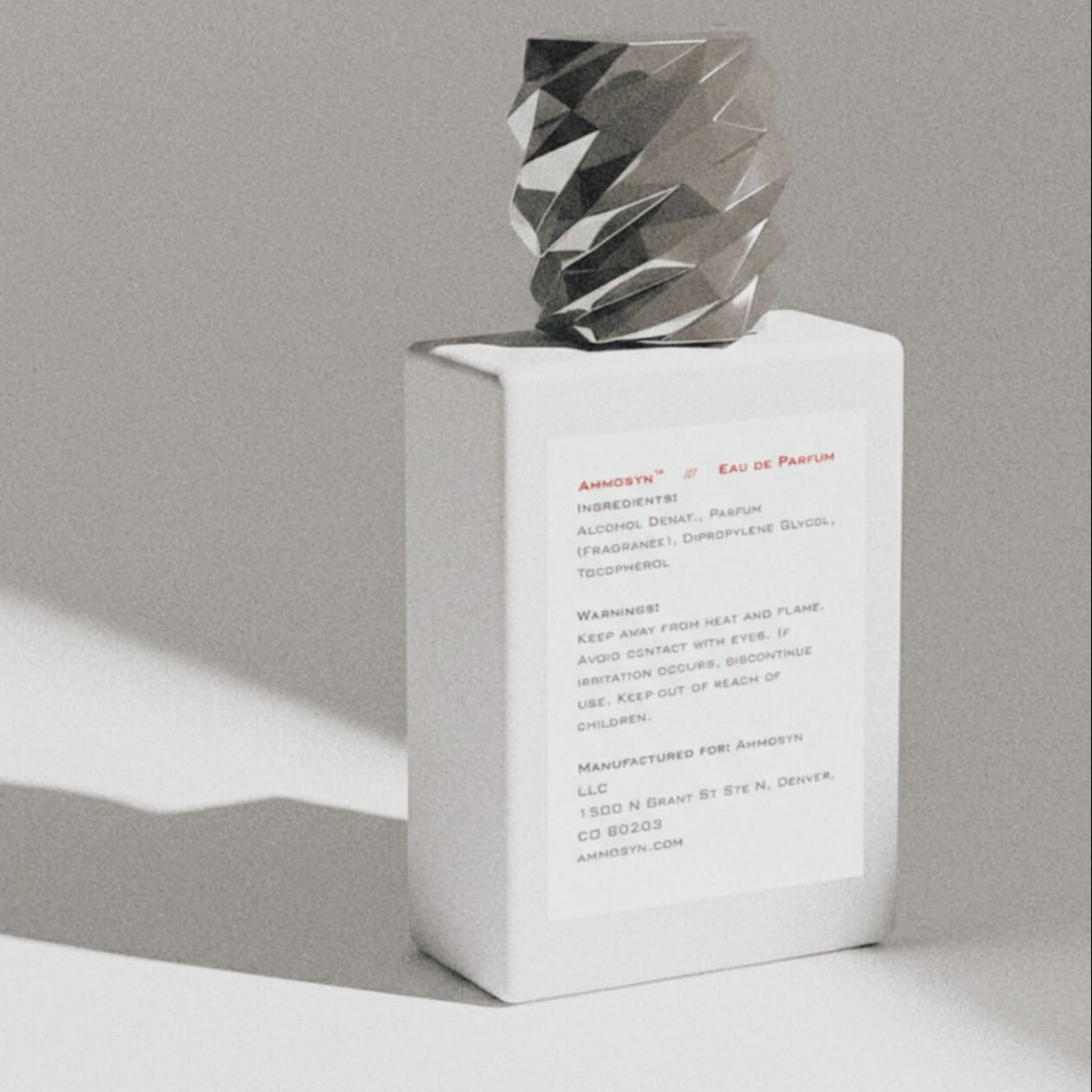 White perfume bottle with silver cap on a gray background