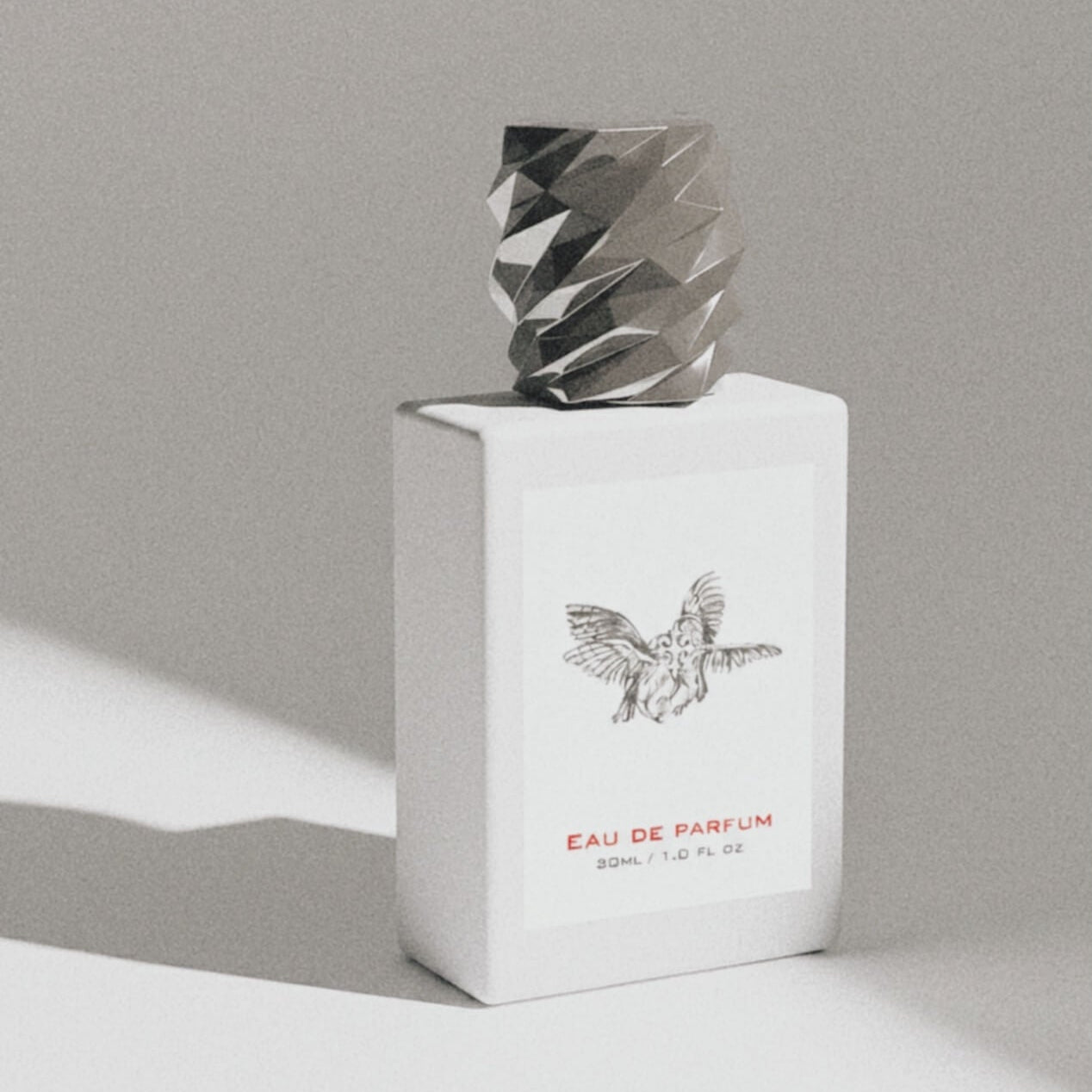 White perfume bottle with silver cap on a gray background