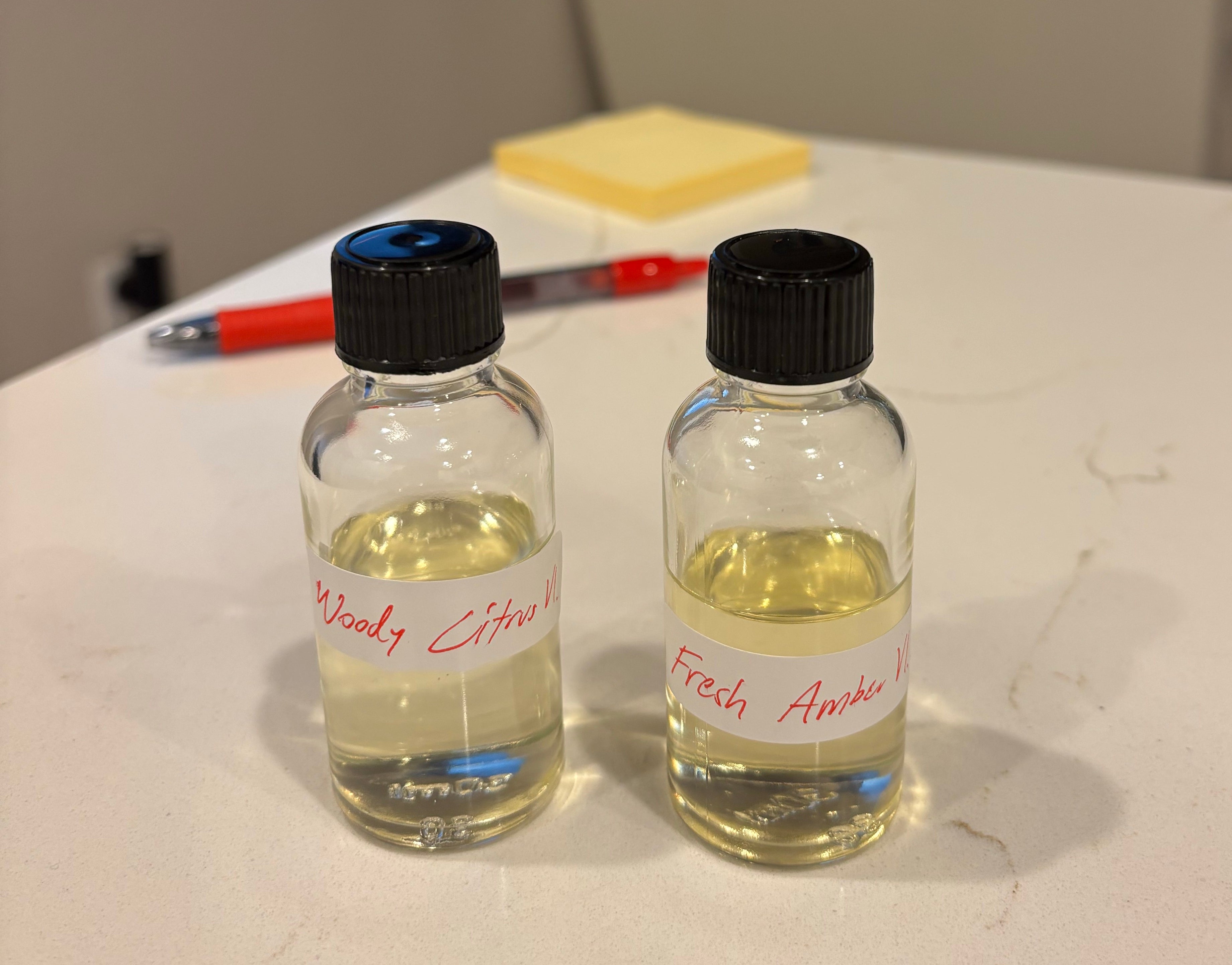 Two small bottles with black caps and labels on a white surface.