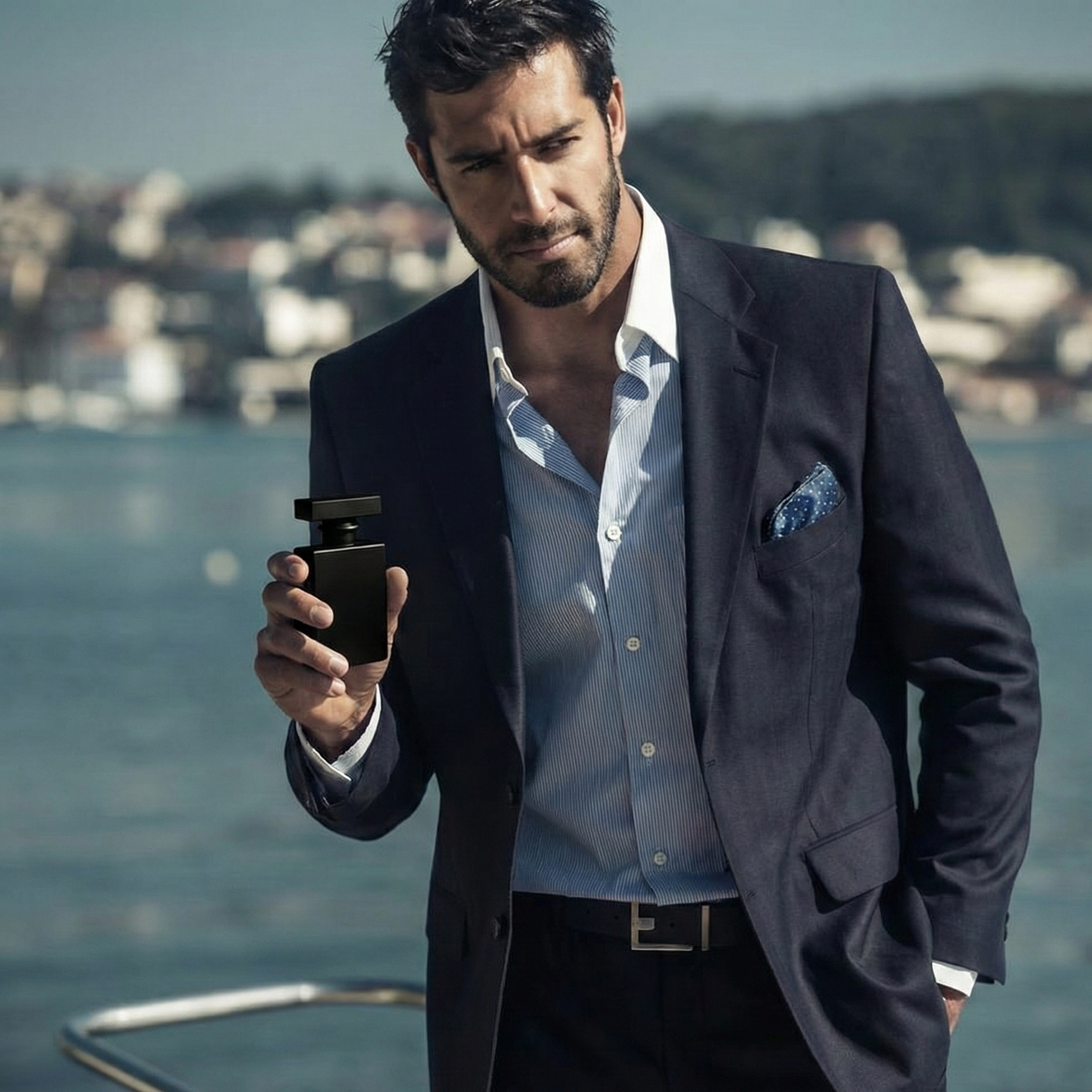 Man in a suit holding Ammosyn perfume bottle by a waterfront