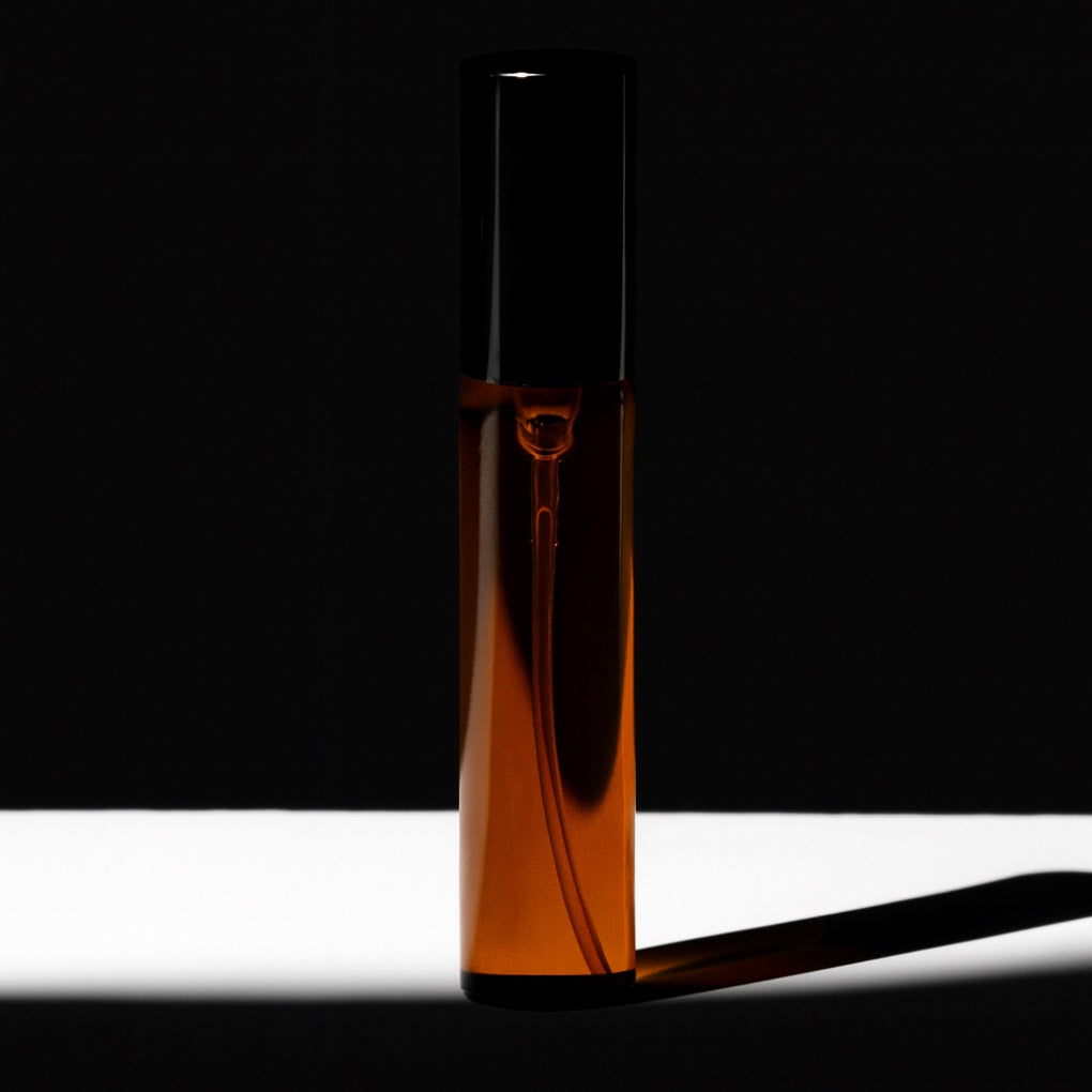 Brown glass bottle with black cap on a white surface with black background